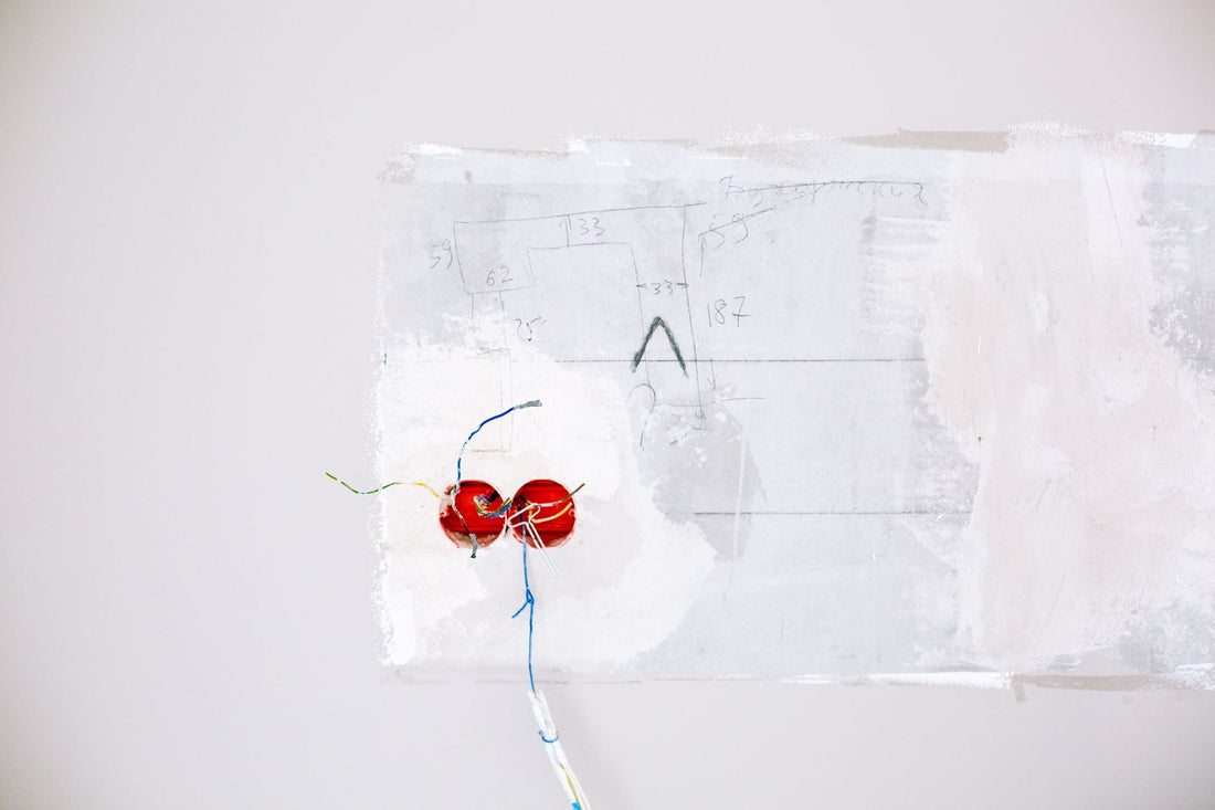 Exposed low-voltage electrical wiring coming out of a white wall during a home renovation
