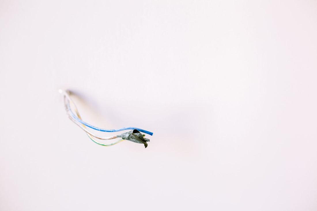 Thermostat wires protruding from a white wall after the thermostat has been removed