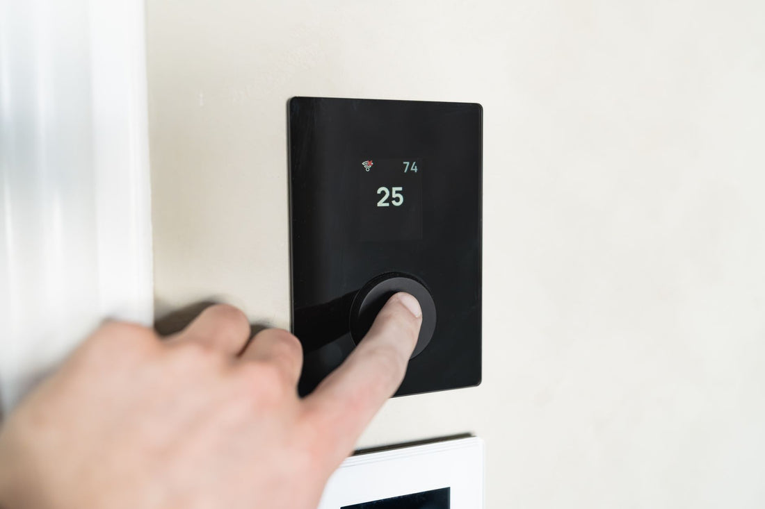 Hand adjusting a modern smart thermostat on a wall