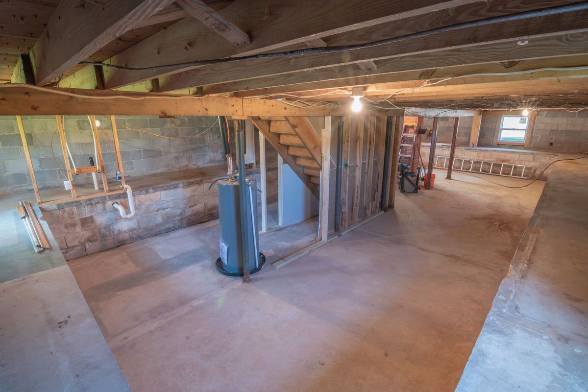 Empty basement with exposed beams and pipes