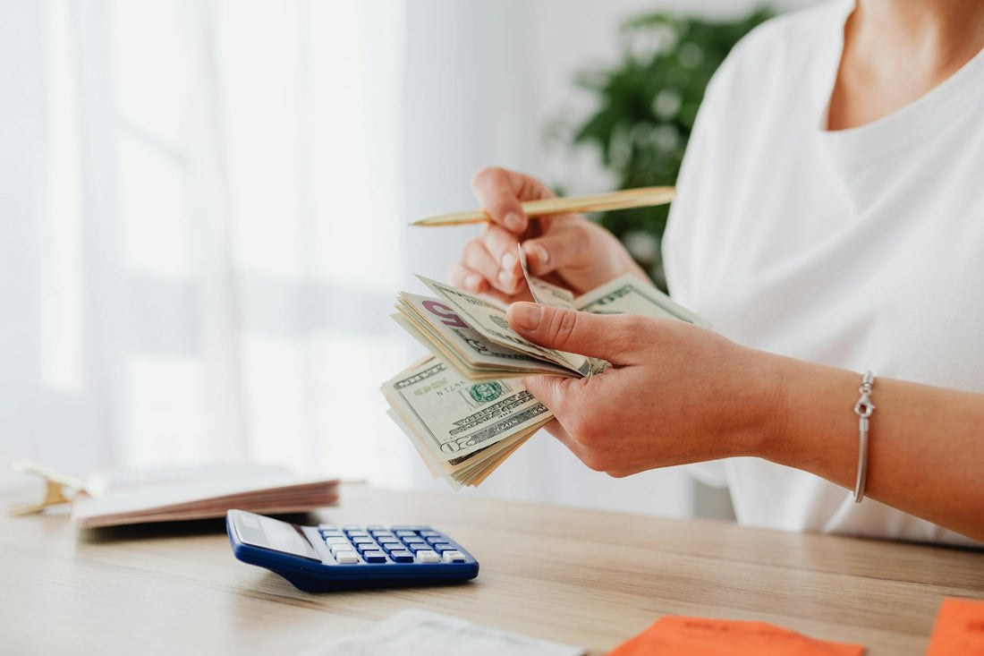 Woman calculating finances at home with US dollar bills and a calculator