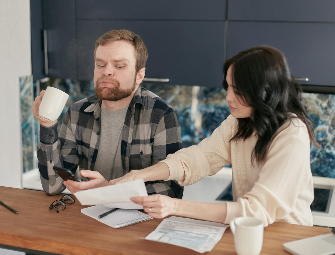 A couple looking worried while reviewing bills at their kitchen table