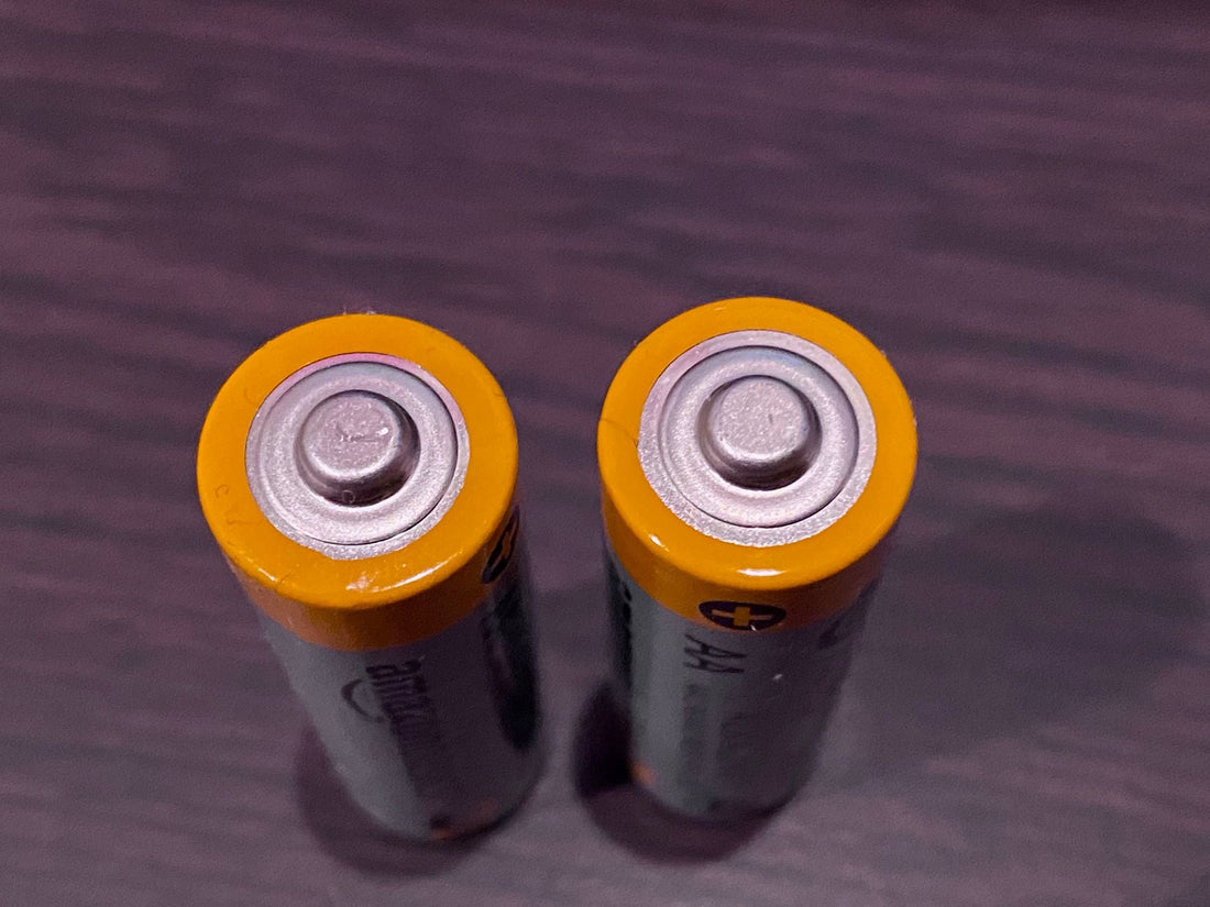 Close-up of two AA batteries on a dark surface